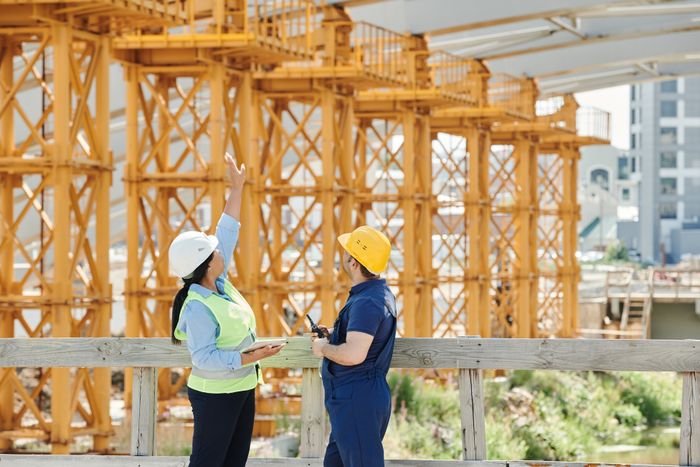 مهندسون يناقشون مخططات في موقع إنشائي
